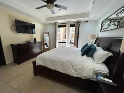 a bedroom with a bed with a ceiling fan and a television at Apartamento de Lujo en Playa Jacó, Frente al Mar, Wifi, AC, Parqueo Privado y Piscinas in Jacó