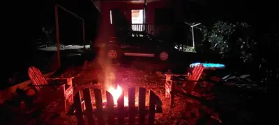 a fire in a yard with two chairs and a car at Chalet El Riachuelo in La Suiza