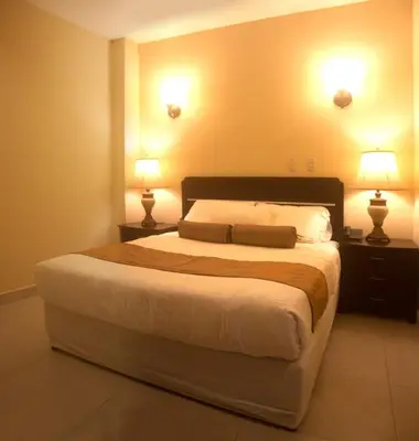 a bedroom with a large bed with two lamps at Hotel Novo in San José