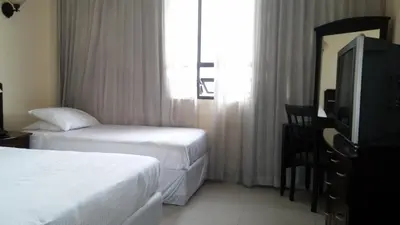 a hotel room with two beds and a television at Hotel Novo in San José