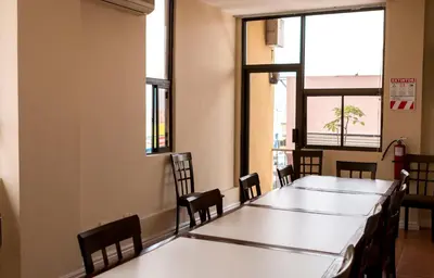 a table and chairs in a room with windows at Hotel Novo in San José