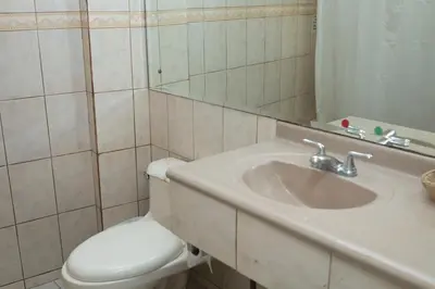 a bathroom with a toilet and a sink and a mirror at Hotel Novo in San José