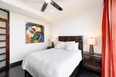 a bedroom with a white bed and a painting on the wall at Condo La Perla 163, Ocean View 3 Bedroom Penthouse in Tamarindo