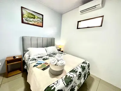 a small bedroom with a bed with flowers on it at Oasis Arenal Villa Downtown Arenal Volcano View in Fortuna