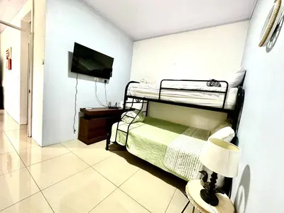 a bedroom with two bunk beds and a flat screen tv at Oasis Arenal Villa Downtown Arenal Volcano View in Fortuna
