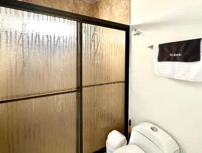 a bathroom with a toilet and a sliding shower door at Oasis Arenal Villa Downtown Arenal Volcano View in Fortuna