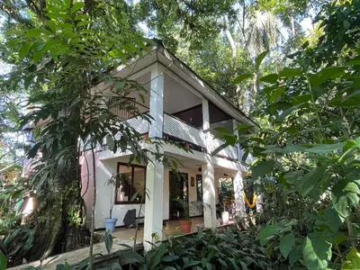 a small white house surrounded by trees at Casa y Cabaña Jaguar Tortuguero in Tortuguero