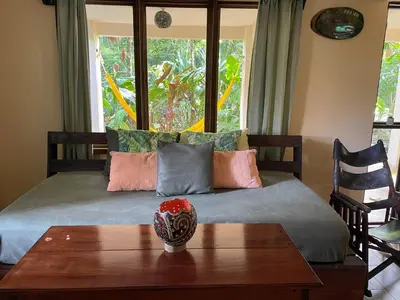 a bedroom with a bed with a table and a window at Casa y Cabaña Jaguar Tortuguero in Tortuguero