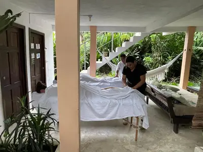 a woman is making a bed on a porch at Casa y Cabaña Jaguar Tortuguero in Tortuguero