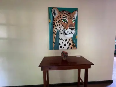 a painting of a leopard on a wall next to a table at Casa y Cabaña Jaguar Tortuguero in Tortuguero
