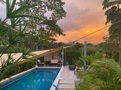 a house with a swimming pool with a sunset in the background at Apartamento con Terraza y Vista al Jardín in Uvita