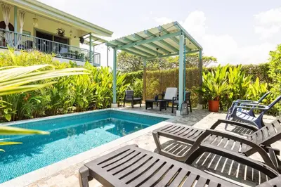 a swimming pool with chairs and a pergola at Beautiful studio-apartment near the beach in Uvita