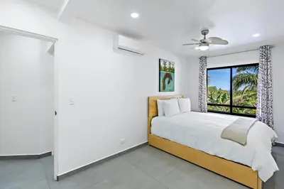 a white bedroom with a bed and a window at Modern Split-Level 2-Bedroom Condo with Pools, Terrace & Easy Beach Access in Coco