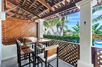 a patio with a wooden table and chairs on a balcony at Modern Split-Level 2-Bedroom Condo with Pools, Terrace & Easy Beach Access in Coco