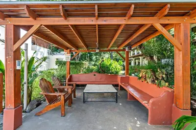 a wooden pergola with a ping pong table and chairs at Modern Split-Level 2-Bedroom Condo with Pools, Terrace & Easy Beach Access in Coco
