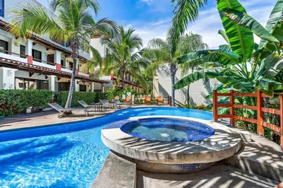 a pool with a hot tub in a yard with palm trees at Modern Split-Level 2-Bedroom Condo with Pools, Terrace & Easy Beach Access in Coco