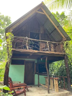 a small building with a balcony and a bench at Cabina Playa Cedros in Cóbano