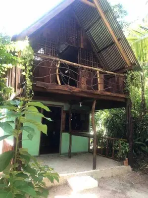 a building with a thatched roof on top of it at Cabina Playa Cedros in Cóbano