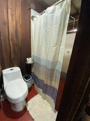 a bathroom with a toilet and a shower curtain at Cabina Playa Cedros in Cóbano