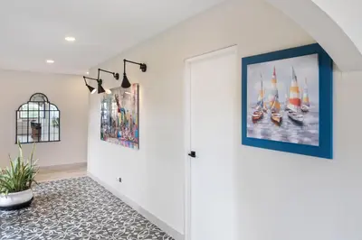 a hallway with a painting of boats on the wall at Luxe Tropical Villa with Sparkling Infinity Pool, Panoramic Ocean Views & Community Amenities in Playa Flamingo