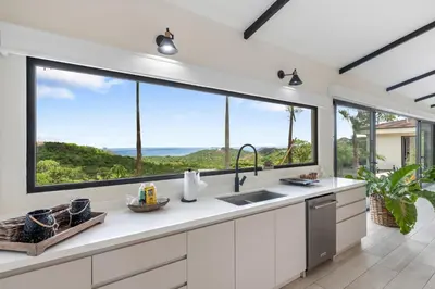 a kitchen with a large window overlooking the ocean at Luxe Tropical Villa with Sparkling Infinity Pool, Panoramic Ocean Views & Community Amenities in Playa Flamingo