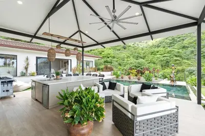an outdoor patio with white furniture and a pool at Luxe Tropical Villa with Sparkling Infinity Pool, Panoramic Ocean Views & Community Amenities in Playa Flamingo
