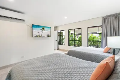 a white bedroom with two beds and windows at Luxe Tropical Villa with Sparkling Infinity Pool, Panoramic Ocean Views & Community Amenities in Playa Flamingo