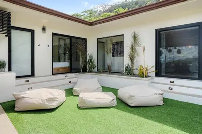 a room with two white bean bags on a green carpet at Luxe Tropical Villa with Sparkling Infinity Pool, Panoramic Ocean Views & Community Amenities in Playa Flamingo