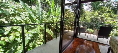 a room with a balcony with a view of plants at Arenal Getaway in Fortuna