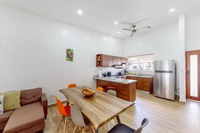 a living room with a wooden table and a kitchen at Casa Eureka in Herradura
