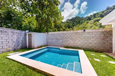 a swimming pool in a yard next to a brick wall at Casa Eureka in Herradura