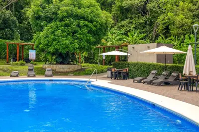 a swimming pool with chairs and tables and umbrellas at Casa Eureka in Herradura