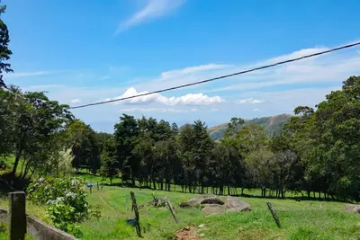 a field of grass with trees and mountains in the background at Cabaña Indira in Monteverde Costa Rica