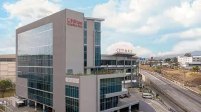an office building with a sign on top of it at Hilton Garden Inn San Jose Airport City Mall in Alajuela City