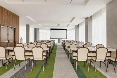 a conference room with tables and chairs and a projector screen at Hilton Garden Inn San Jose Airport City Mall in Alajuela City