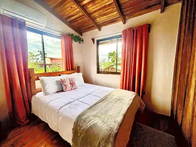 a bedroom with a bed and two windows at Cabañas Litos #1 in Fortuna