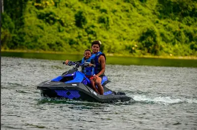 a man and a child on a jet ski in the water at Cabañas Litos #1 in Fortuna