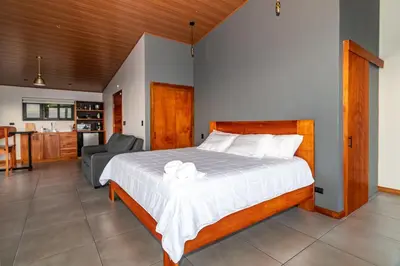 a bedroom with a large bed and a kitchen at Villas Páramo Cloud Forest Hotel in División