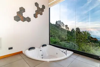 a bath tub in a room with a large window at Villas Páramo Cloud Forest Hotel in División