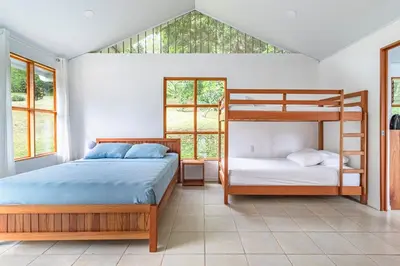 a bedroom with two bunk beds and two windows at Finca Mango - 40 acre paradise in Roble