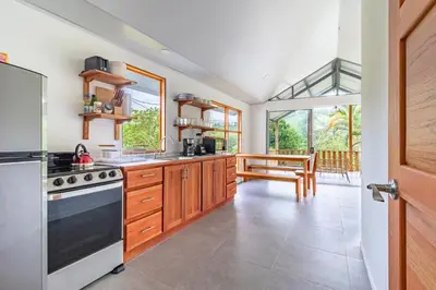 a kitchen with wooden cabinets and a large window at Finca Mango - 40 acre paradise in Roble