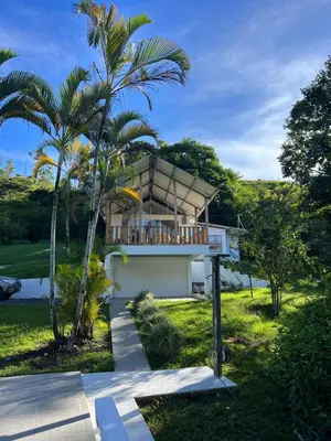 a house with a balcony with a palm tree at Finca Mango - 40 acre paradise in Roble