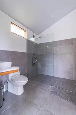 a bathroom with a toilet and a glass shower at Finca Mango - 40 acre paradise in Roble