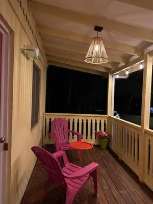 a porch with pink chairs and a table and a chandelier at Villas La Paillote Costa Rica in Puntarenas