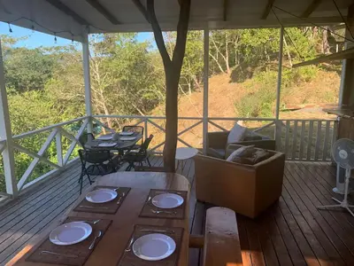a porch with a table and chairs on a deck at Villas La Paillote Costa Rica in Puntarenas