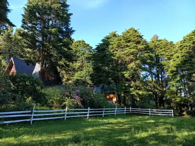 a white fence in a field with trees at Les Chalets Costa Rica in Zarcero