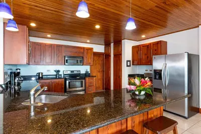 a kitchen with wooden cabinets and a stainless steel refrigerator at Casa Antonelli 4br Infinity Pool Pet Friendly in Playa Hermosa