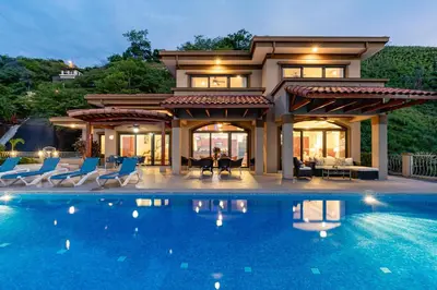 a house with a swimming pool in front of a house at Casa Antonelli 4br Infinity Pool Pet Friendly in Playa Hermosa