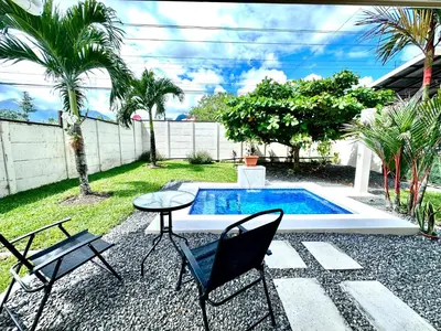 a patio with chairs and a table and a pool at Oasis Arenal Villa Pool & Arenal Volcano View in Fortuna