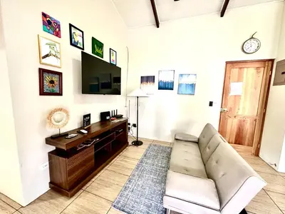 a living room with a couch and a tv at Oasis Arenal Villa Pool & Arenal Volcano View in Fortuna